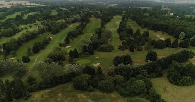 Large English Golf Course with trees and green fairways. Overcast day