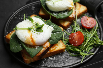 Delicious poached egg sandwiches served on slate board, closeup