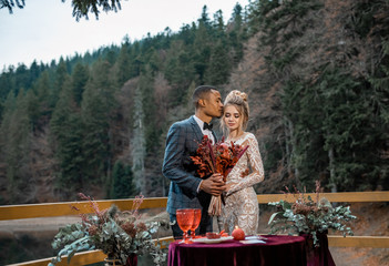 Standing couple in the forest at mountain sunset. Modern couple and ideas for the ceremony. Wedding in American style. Beautiful mountain landscape view.
