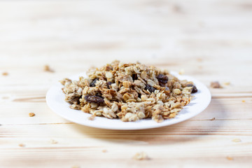 Heap of dry muesli in white plate on wooden background