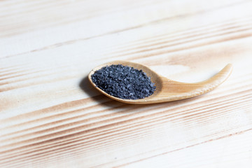 Black (burned with powder) salt in  spoon on wooden background