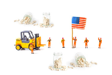 miniature worker with herb capsule pills spilling out off bottle isolated on white background.Image for Medical Concept.