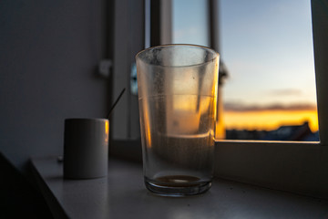 Cup and glass at the window in the sunset