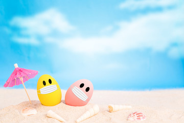 Fototapeta na wymiar colorful eggs wear fabric mask on white sand beach over cloudy sky background,image for social distancing holiday or Happy weekend concept.