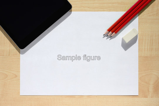 Red pencils and a tablet lie on a white sheet.