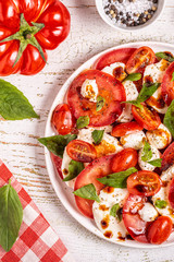 Italian caprese salad with sliced tomatoes, mozzarella cheese, basil, olive oil, balsamic vinegar.