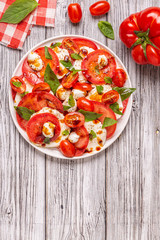 Italian caprese salad with sliced tomatoes, mozzarella cheese, basil, olive oil, balsamic vinegar.