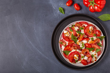 Italian caprese salad with sliced tomatoes, mozzarella cheese, basil, olive oil, balsamic vinegar.