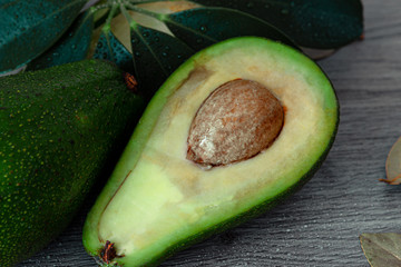 avocado, cut avocado, walnut, core and greens on a gray wood background