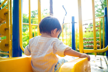 Little asian boy playing plastic slider kid at the playground city park green tree nature...
