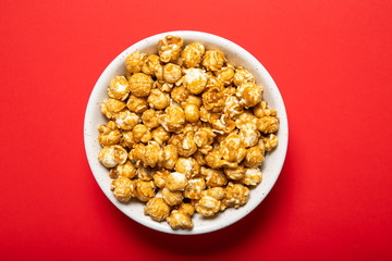 Plate with caramel popcorn on a red background