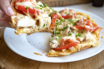 slice of pizza on a pita bread with chicken, tomatoes and stretching cheese