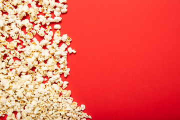 Delicious popcorn on a red background. Top view, place for text.