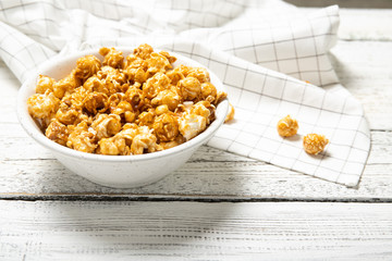 Plate with caramel popcorn on a wooden background. Place for text