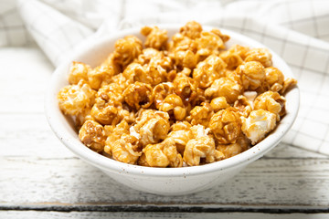 Plate with caramel popcorn on a wooden background. Close-up