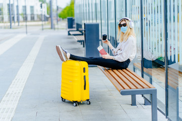 Woman traveler in medical protective mask holds passport during affected by flight delay and cancelled travel and vacation. Travel ban due to coronavirus outbreak and covid ncov virus epidemic