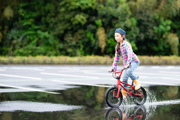 水溜まりで自転車に乗る女の子