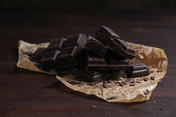Pieces of delicious dark chocolate on wooden table