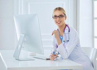 Portrait of young female doctor sitting at desk in hospital