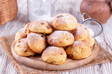 Homemade cottage cheese buns with raisins and icing sugar on a white table