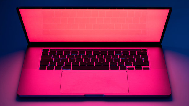 Elegant Laptop Computer View On A Table With Red Screen Light Glow And Dark Blue Background.