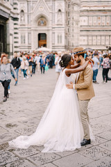 Interracial wedding couple. Wedding in Florence, Italy. African-American bride and Caucasian groom cuddling in Piazza del Duomo.