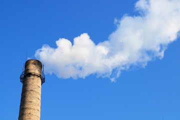 plant tubes with gray smoke on blue sky, chemical plant towers of nuclear power plant against the...