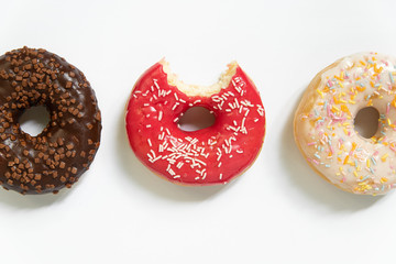 Donut day. Bitten colored donuts with colorful sprinkles on white background. Copy space, close-up