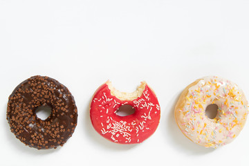 Donut day. Bitten colored donuts with colorful sprinkles on white background. Copy space, close-up
