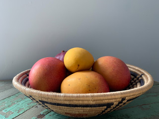 Mangoes in Woven Bowl on Wood Background