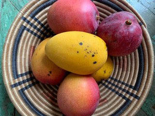 Mangoes in Woven Bowl on Wood Background