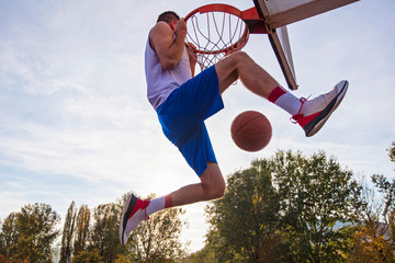 Young man jumping and making a fantastic slam dunk playing streetball, basketball. Urban authentic. © FS-Stock