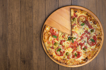 Photo of Pizza Marguerita made with Mozzarella Cheese, tomatoes, basil leaves and green olives, served on a wooden board. Top photo with elements on the right with space on the left for writing