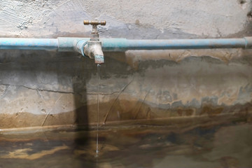 Water from old bass faucet connect to the blue pvc pipe flowing into water surface of bath made of...