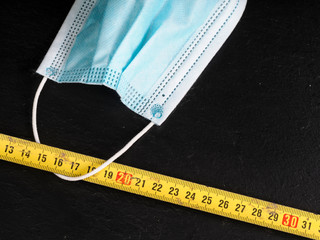 coronavirus icons as facial mask and folding meter on black background representing social...
