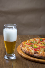 Pizza Marguerita made with Mozzarella Cheese, tomatoes, basil leaves and green olives. Glass of beer. Perfect combination for your happy moments. Top space for writing.