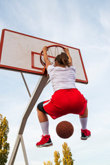 Females playing basketball on street court. Woman streetball player making slam dunk in a...