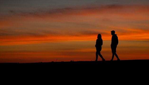 Mother and son silhouettes walking in the beach path at sunset, Esposende, Braga, Portugal.