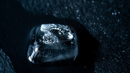Close-up of melting blue ice cubes on black background	
