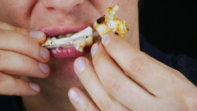 Unrecognizable man with crooked teeth eats fried chicken.Chews wings BBQ.