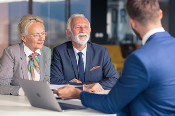 Positive aged couple consulting with insurance agent