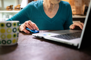 elderly woman using laptop in her kitchen