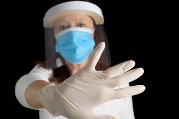 Forgive partially covering the face in which she wears a protective mask, with one hand, with a latex glove, on a black background. Protection for contagions