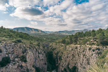 Fototapeta na wymiar Scenic view of a canyon. Spanish hills and dramatic clouds. Mediterranean green and arid landscape.