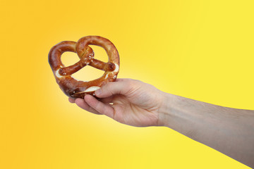 beautiful freshly baked pretzel, German national dish with a golden brown crust in a male hand close-up, the concept of traditional Hesse cuisine, organic food