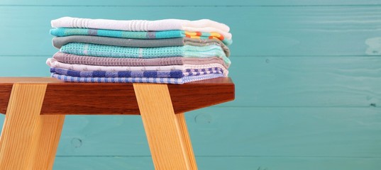 Pile of linen kitchen towels. colorful dish towels stack on a wooden Craft Product stool at wooden...