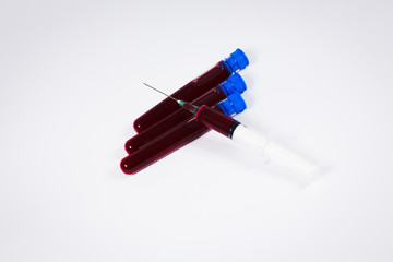 Syringe and blood test tube on white background.