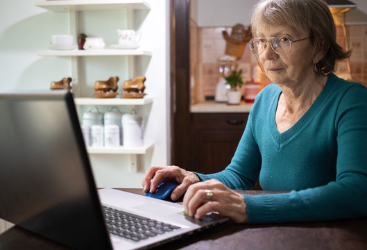 elderly woman using laptop in her kitchen