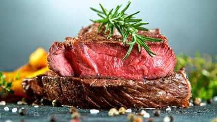 Close-up of tasty beef steak on black stone table, still life.