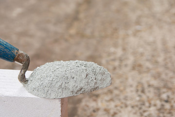 Cement powder or mortar with  trowel put on the Lightweight Concrete brick for construction work..